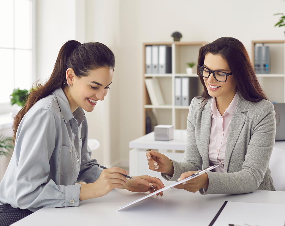 Two women discussing documents in office.