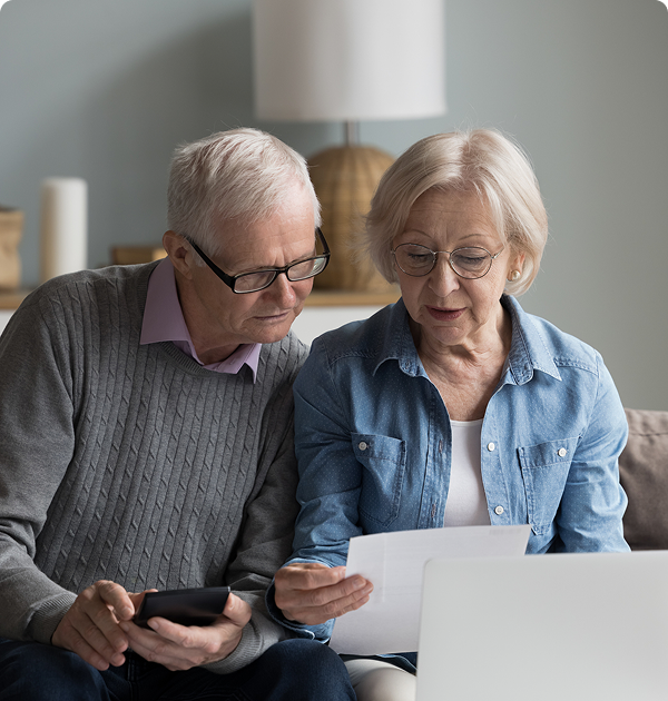 Elderly couple reading documents together at home.
