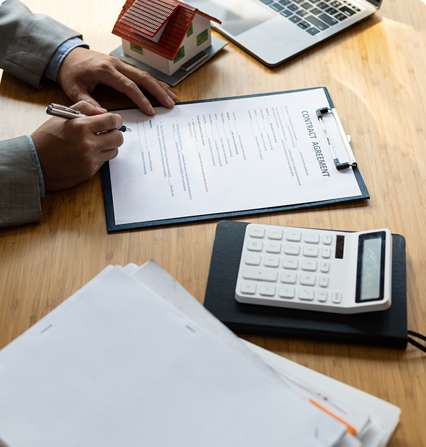 Signing contract agreement with calculator and laptop.