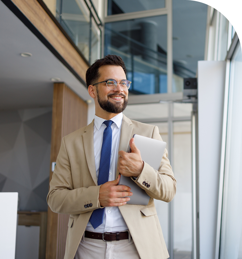 Smiling man holding laptop in office.