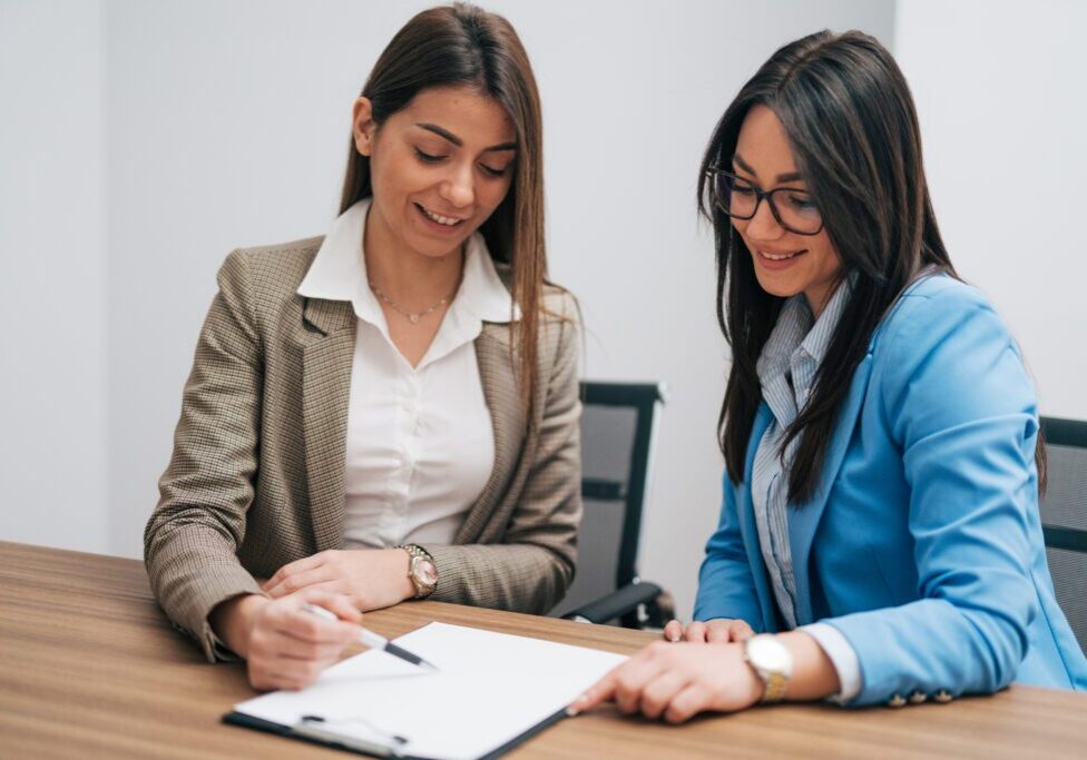Two young business women working together in a modern office